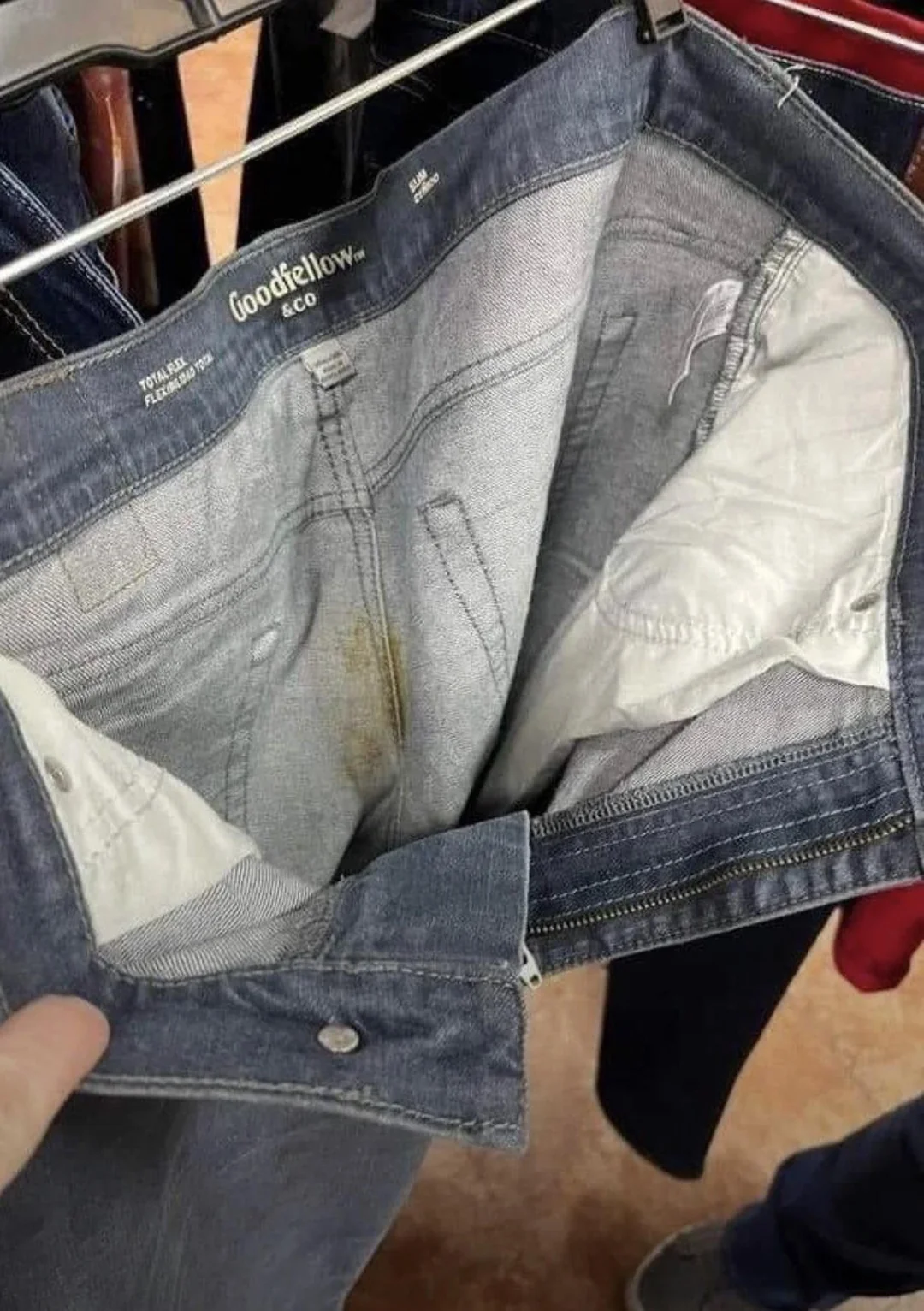 Slightly used denim jeans on a store rack with a brown stain inside